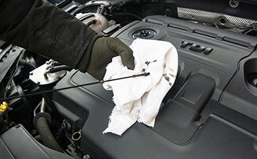 wiping engine oil dipstick of a car